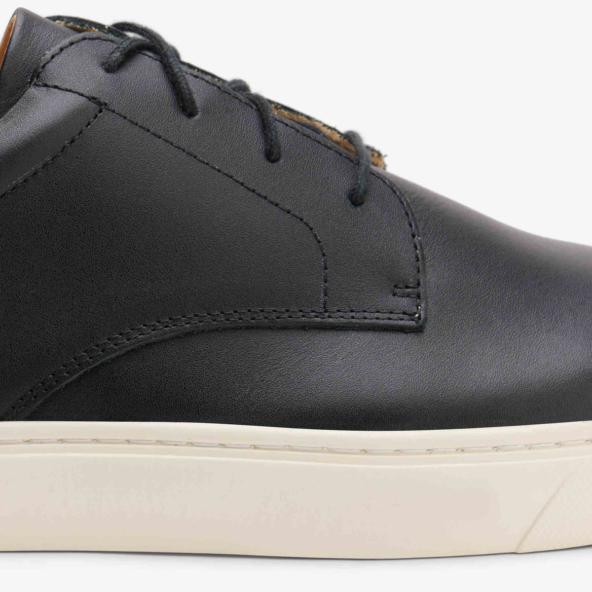 Close-up of a black leather Diego Everyday Sneaker with matching laces and a thick white rubber sole.