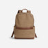 Tan fabric backpack with brown leather trim, a top handle, and side pockets on a white background.