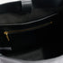 Interior view of a black leather bag featuring a zippered pocket with a gold-tone metal pull and a magnetic strap closure.