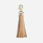 Single almond leather tassel bag charm with a gold metal clasp and NISOLO embossed on the top band.