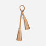 Two tan leather tassels hanging from a looped strap on a white background.