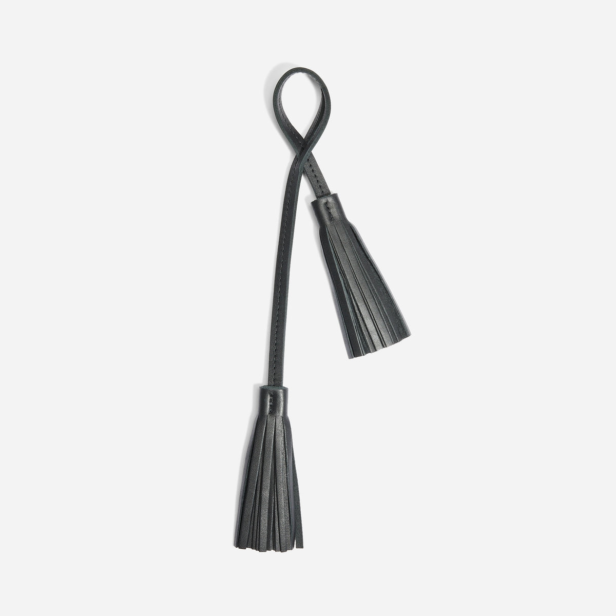 Black leather bag charm featuring two fringed tassels hanging from a looped strap on a white background.