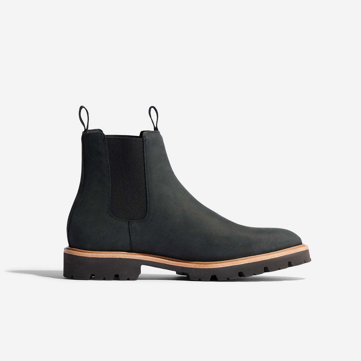 Single black leather Chelsea boot with elastic side panels, pull tabs, and a lugged sole with tan welt.