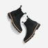 Pair of black leather Chelsea boots with lug soles and elastic side panels, shown from a top-down angle on a white backgro...
