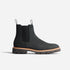 Single black Chelsea boot with elastic side panels, pull tabs, and a lugged sole with a tan welt.