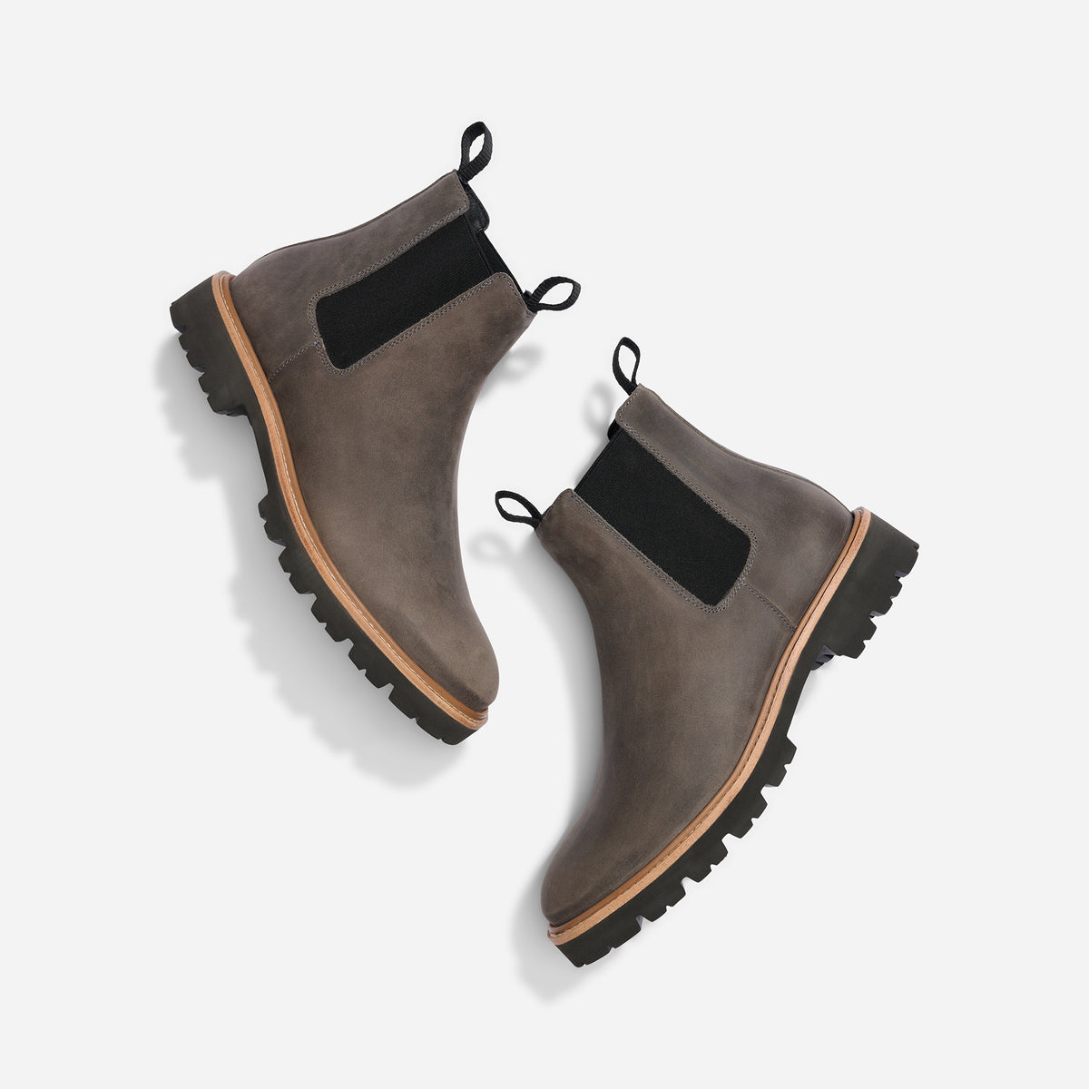 Pair of grey leather Chelsea boots with black elastic side panels and lugged rubber soles on a white background.