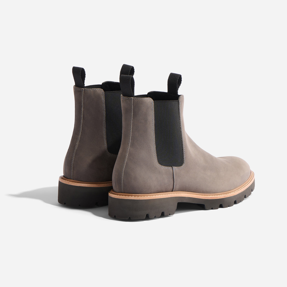 Pair of grey suede Chelsea boots with black elastic side panels and lugged rubber soles on a white background.