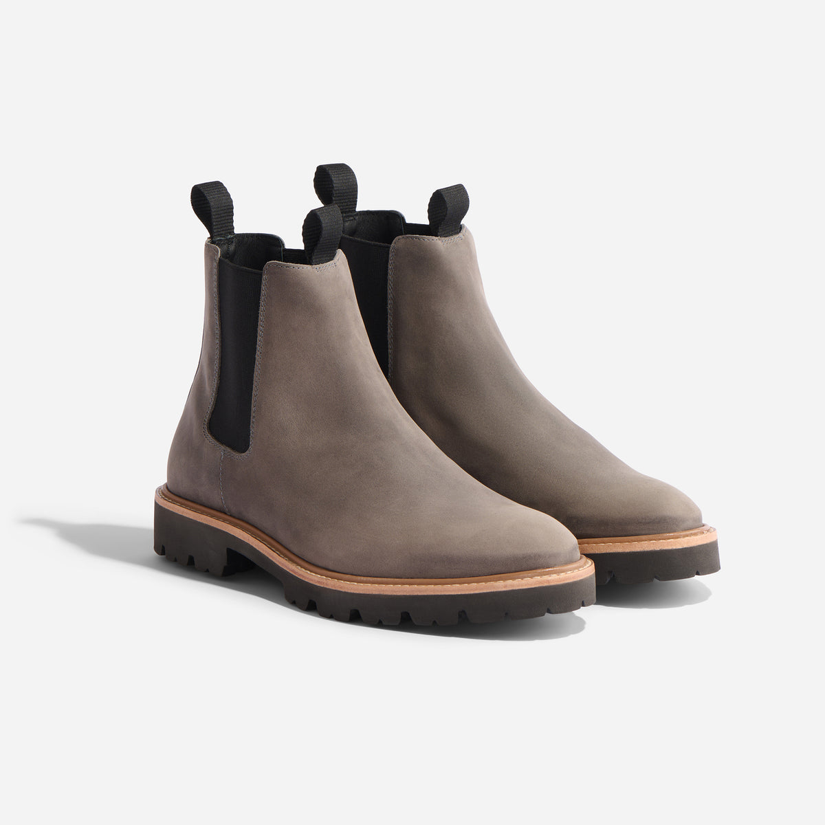 Pair of grey suede Chelsea boots with black elastic side panels, pull tabs, and lugged rubber soles on a white background.