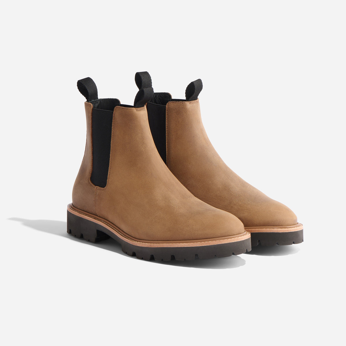 Pair of tobacco brown leather Chelsea boots with black elastic side panels and lugged rubber soles.