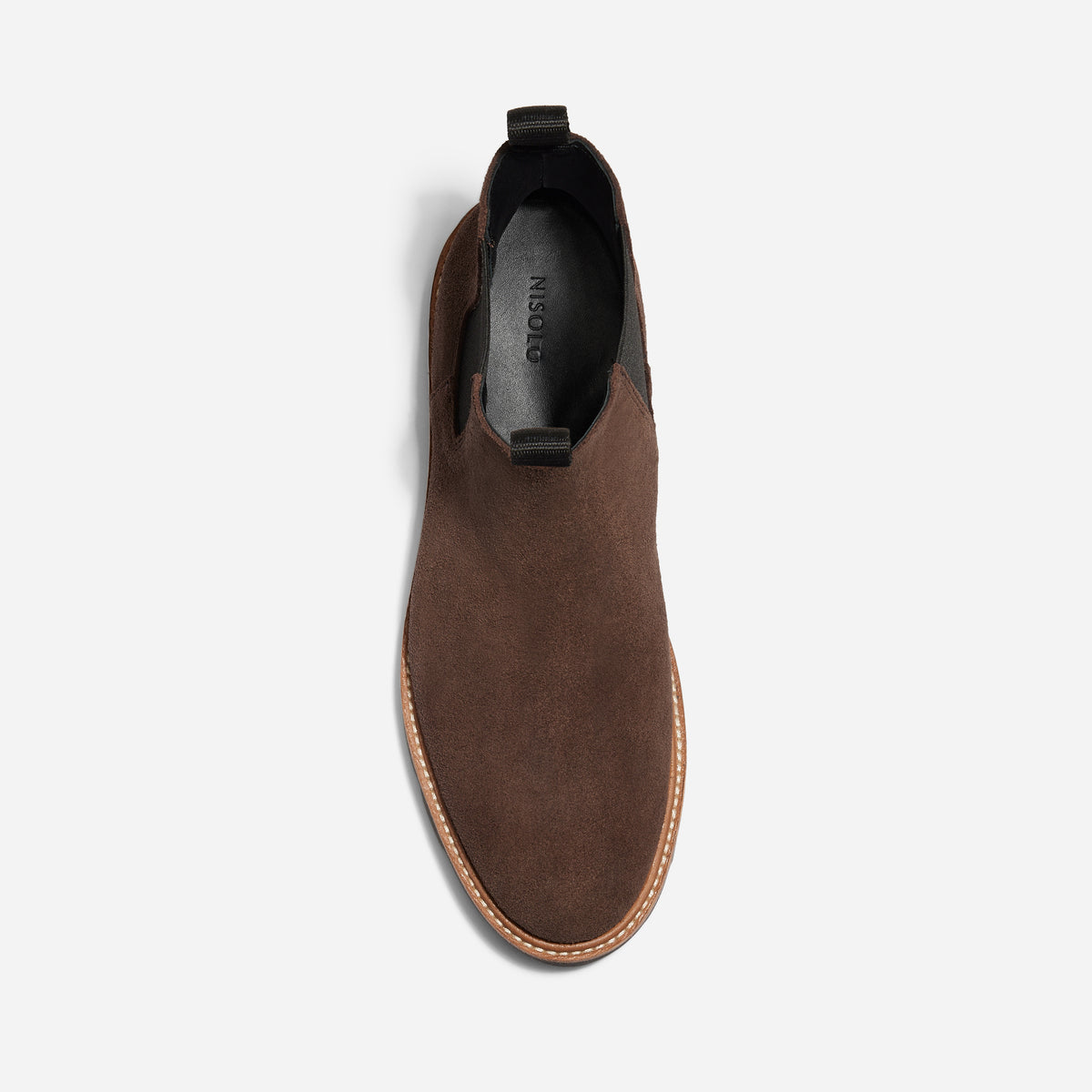 Top view of a single brown suede Chelsea boot with black elastic side panels and NISOLO printed on the black insole.