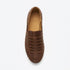 Single brown leather huarache slip on shoe with a woven upper and NISOLO printed on the tan inner sole.