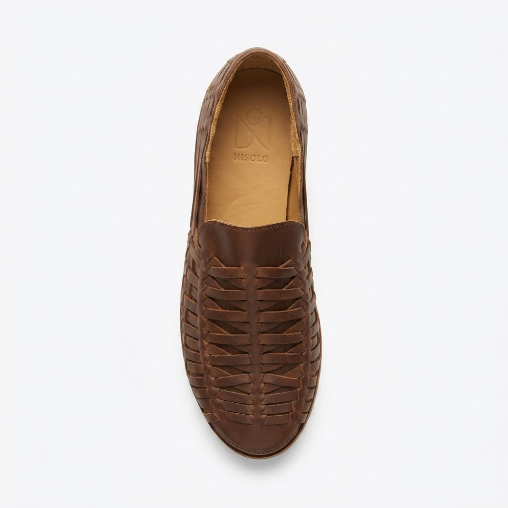 Single brown leather huarache slip on shoe with a woven upper and NISOLO printed on the tan inner sole.