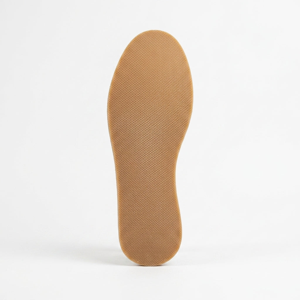 Bottom view of a single tan textured rubber shoe sole against a white background.