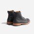 Pair of black leather lace-up boots with tan soles and pull tabs, shown from a rear three-quarter angle on white.