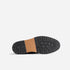 Black rubber lug sole of a boot with a tan leather arch featuring the NISOLO brand name.