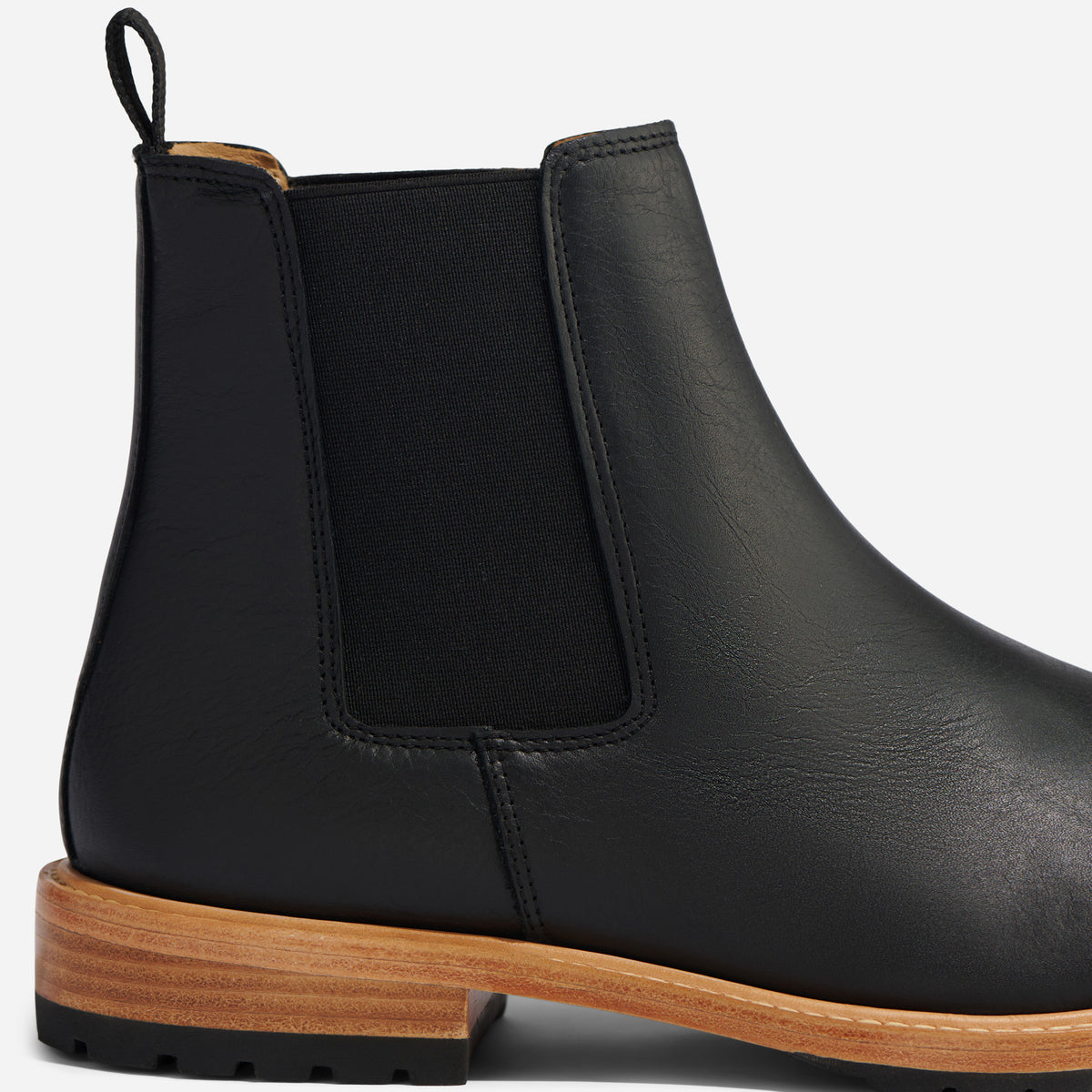 Single black leather Chelsea boot with a black elastic side panel, pull tab, and a light brown wood-look sole.