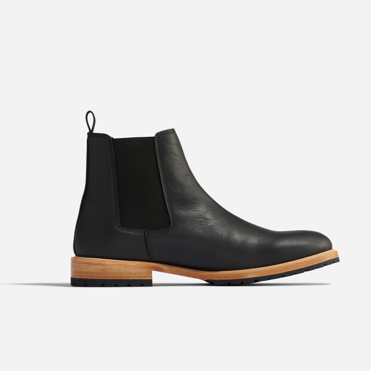 Single black leather Chelsea boot with elastic side panel and light wood-colored sole shown in profile on white background.