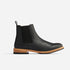 Single black leather Chelsea boot with a tan wood-look midsole, black elastic side panel, and pull tab on a white background.