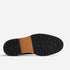 Bottom view of a black lugged rubber outsole with a tan leather waist featuring the NISOLO brand name.