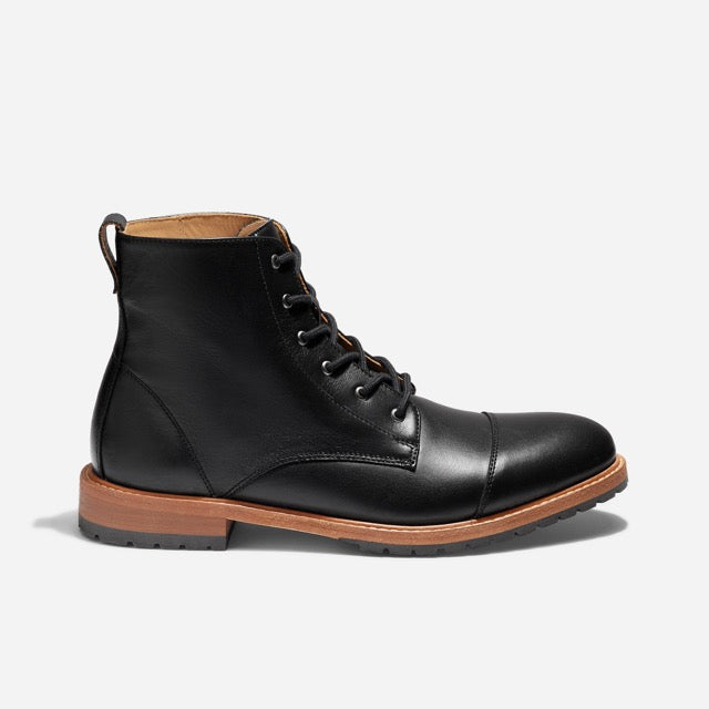 Single black leather cap toe boot with black laces and a brown sole, shown from a side profile against a white background.