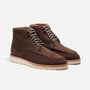 Pair of umber brown suede moc toe boots with white rubber soles and striped laces on a white background.