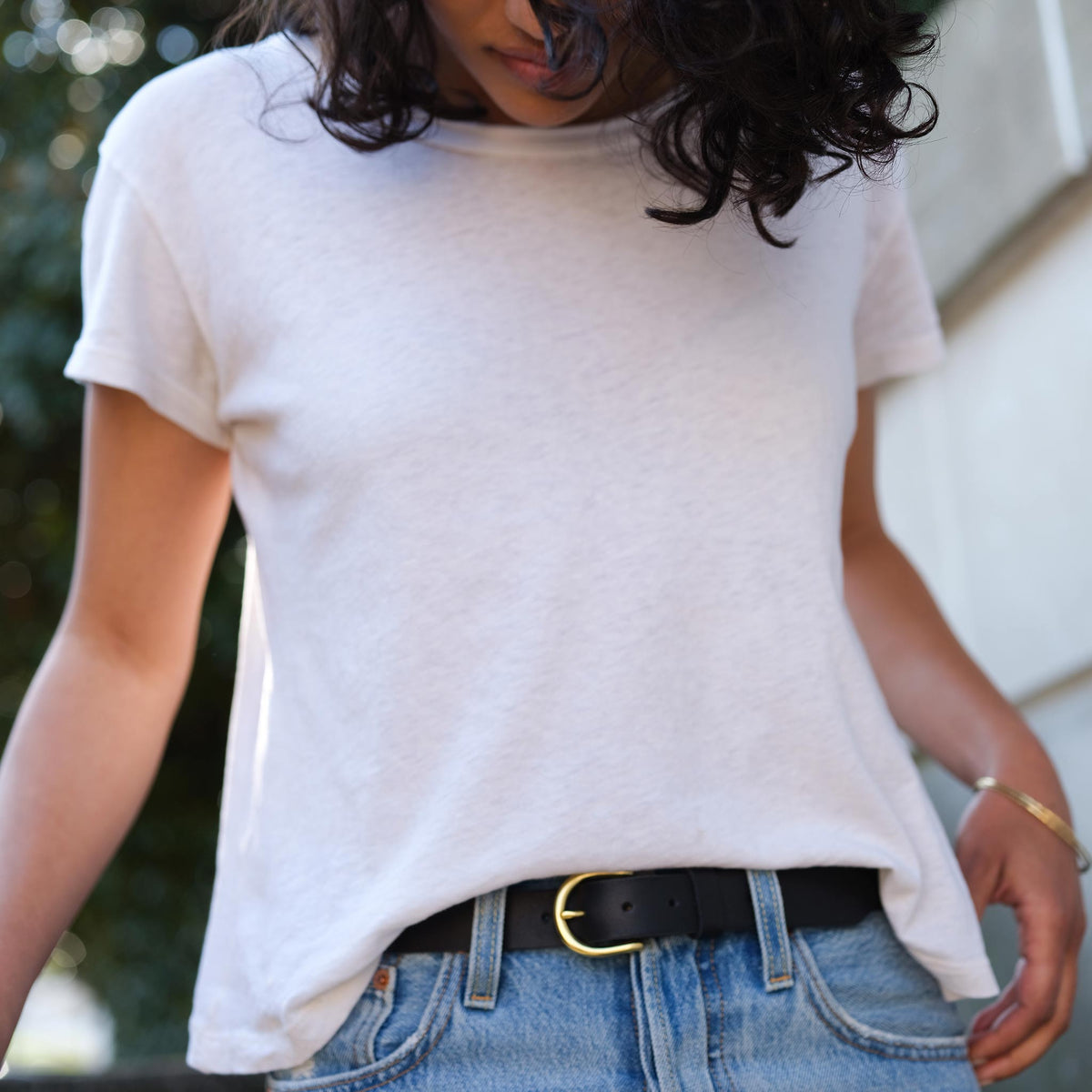Black leather belt with a gold-tone metal buckle worn with blue denim jeans and a white t-shirt.