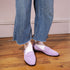 Purple suede Lidia Whipstitch Loafers worn with white socks and denim jeans on a wood floor.