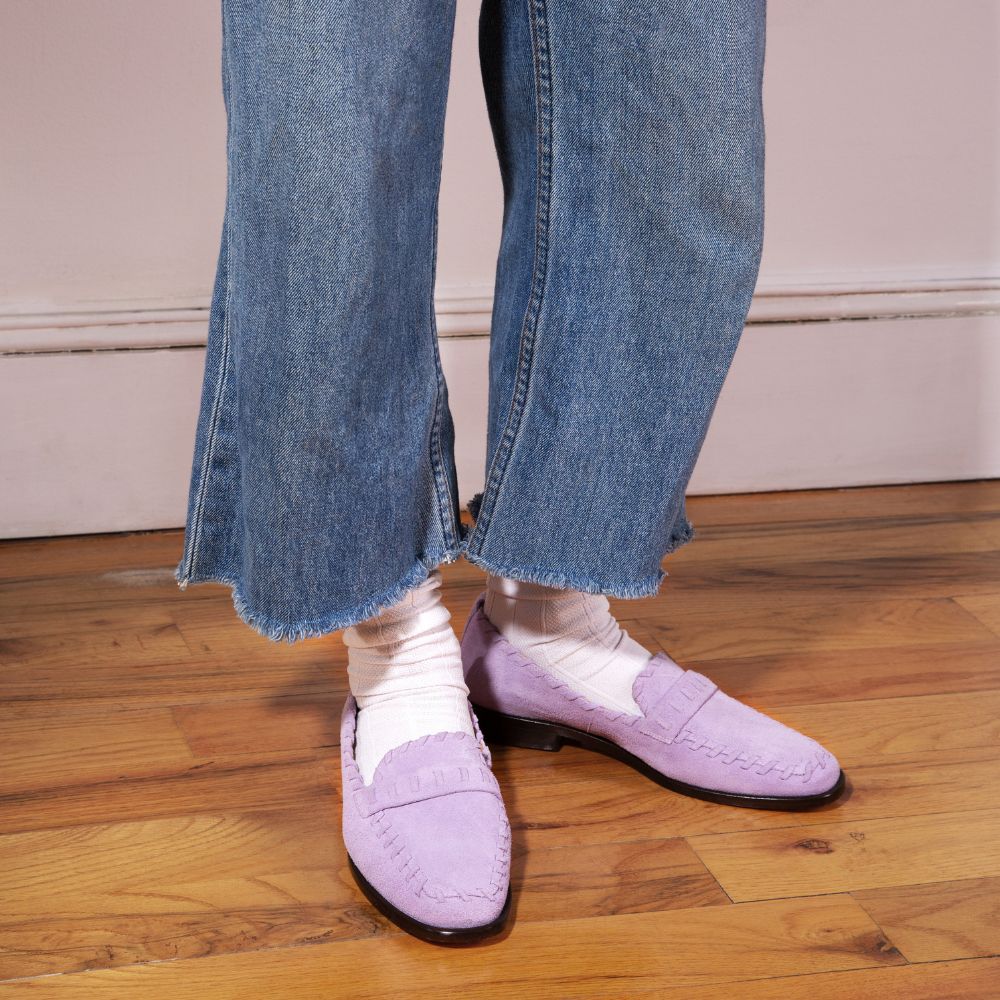 Purple suede Lidia Whipstitch Loafers worn with white socks and denim jeans on a wood floor.