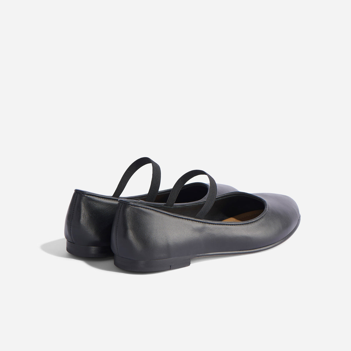 Pair of black leather Bea Go-To Mary Jane flats with elastic straps, shown from a rear three-quarter angle.