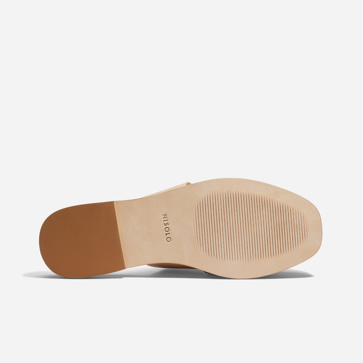 Tan leather sole of a NISOLO mule featuring a textured rubber forefoot and heel tap.