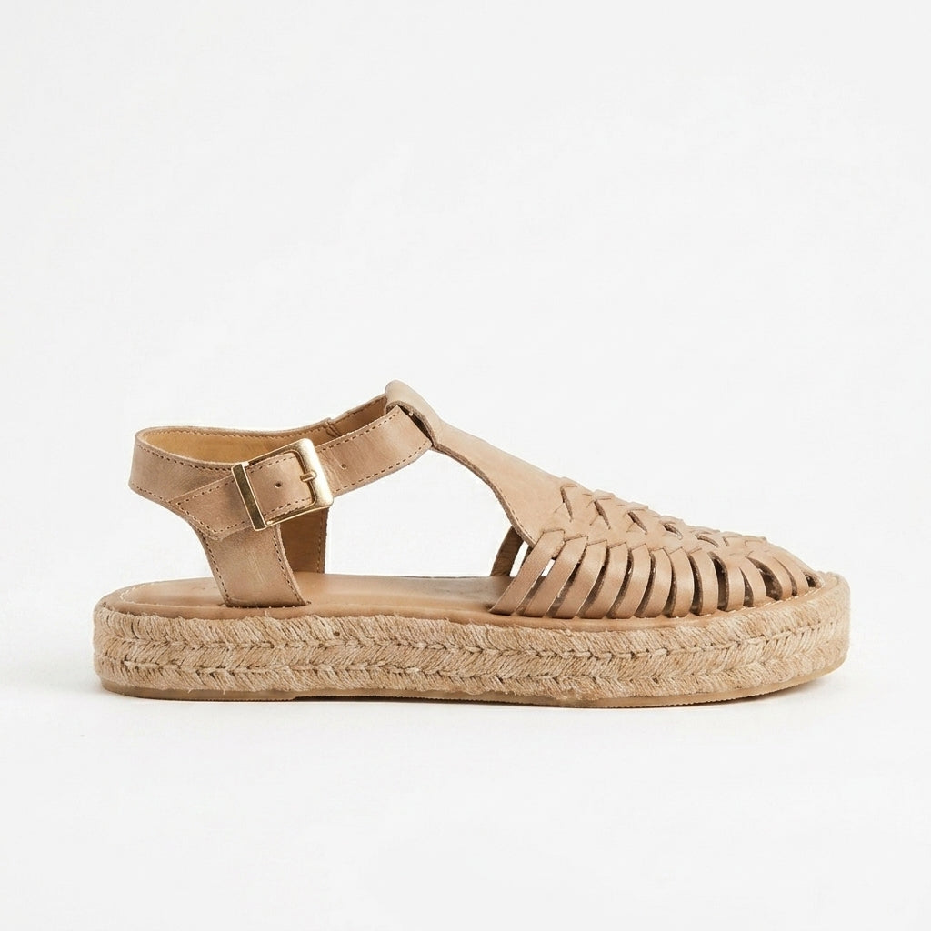 Tan leather T-strap huarache sandal with a woven fiber platform sole and gold buckle on a white background.
