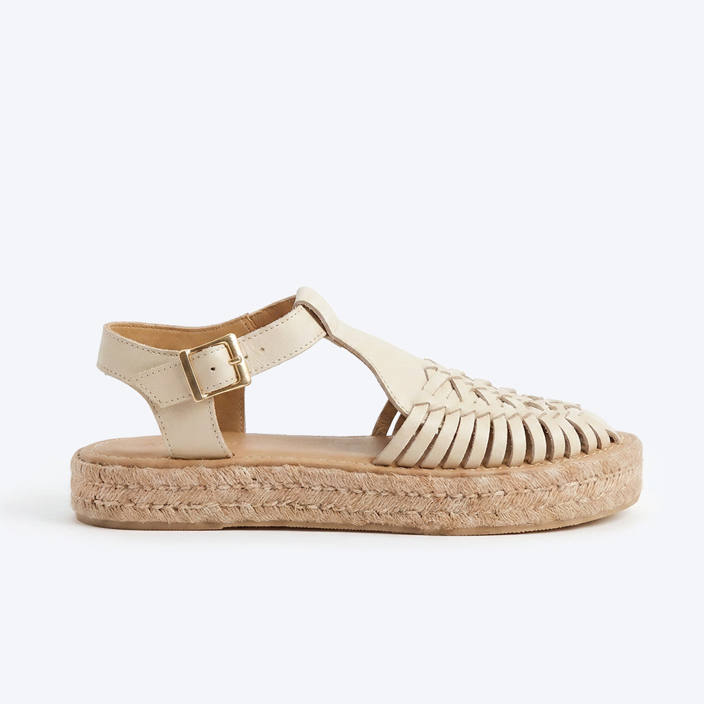 Bone leather huarache T-strap sandal with a woven toe, gold buckle, and jute espadrille platform sole.