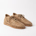 Pair of almond tan woven leather huarache booties with laces on a white background.