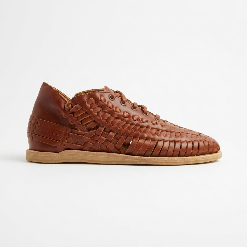 Single brandy-colored woven leather bootie with laces and a flat tan sole shown in profile against a white background.