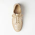 Single gold woven leather bootie with laces and NISOLO printed on the inner sole, viewed from above on a white background.