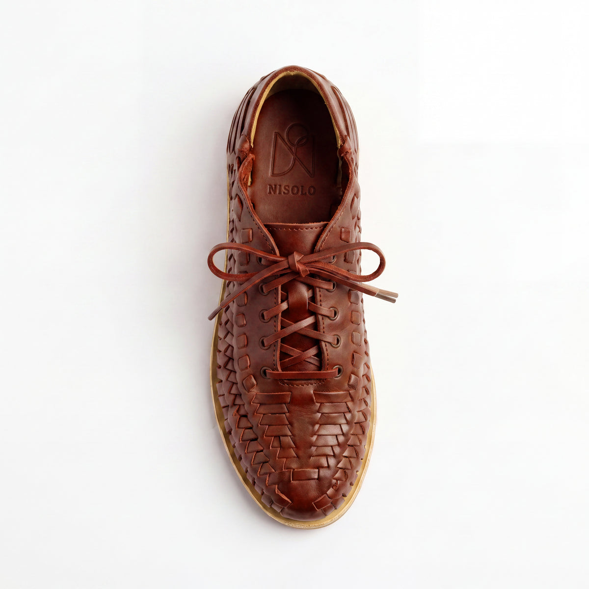 Single brown woven leather bootie with laces and NISOLO printed on the inner sole, viewed from above on a white background.