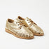 Pair of gold metallic leather huarache oxfords with woven straps and tan laces on a white background.