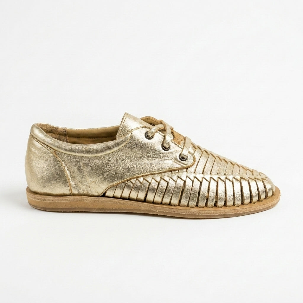 Single metallic gold leather huarache oxford shoe with woven details and tan laces shown from the side on a white background.