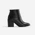 Single black leather ankle boot with a block heel and gold-tone back zipper shown in profile on a white background.