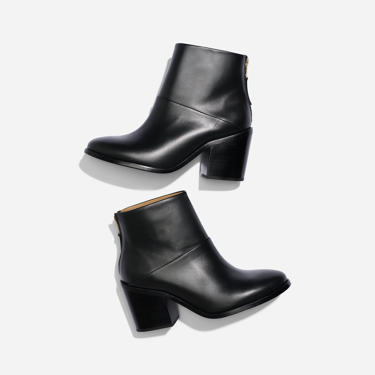 Two black leather ankle boots with block heels and rear zippers shown from a side profile on a white background.