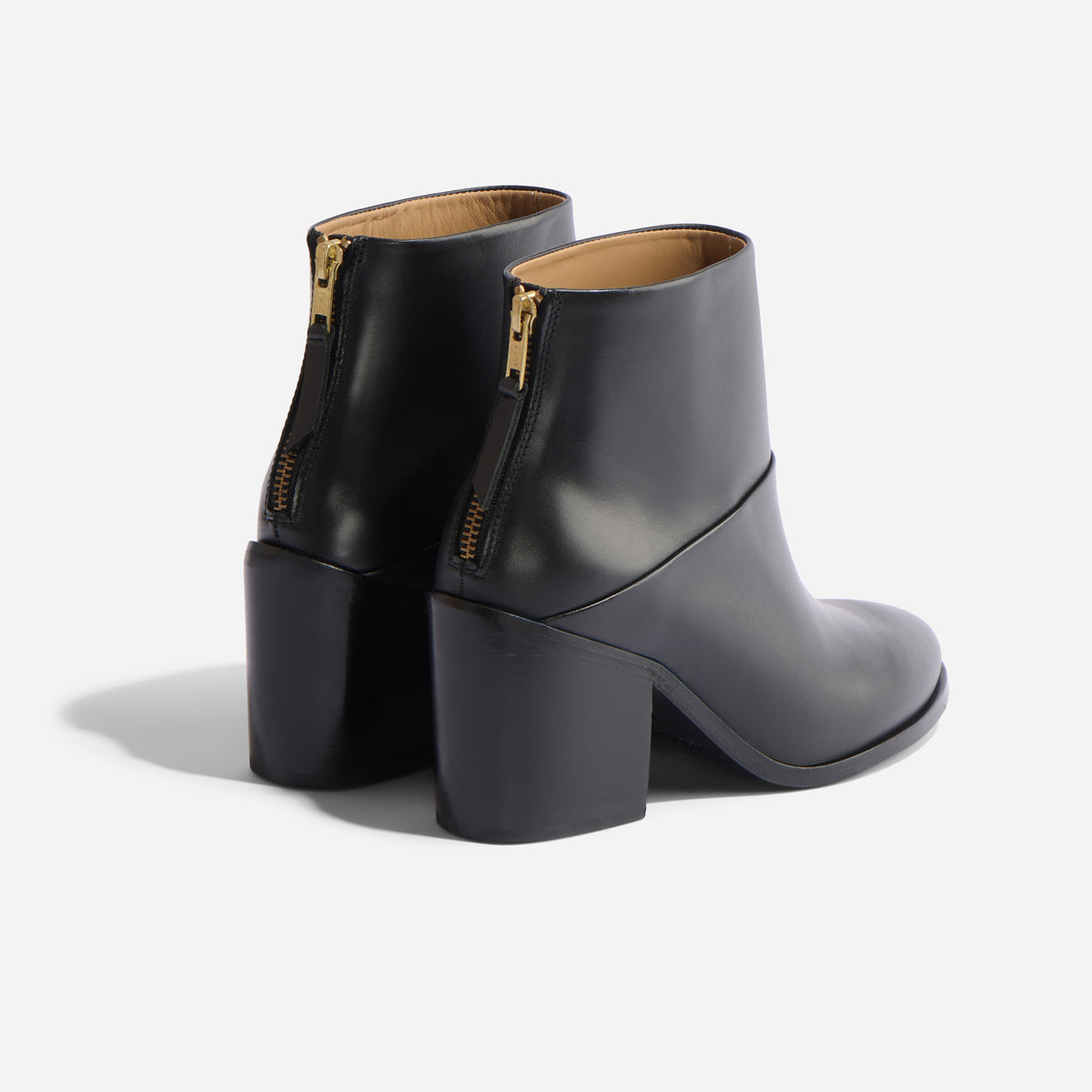 Pair of black leather ankle boots with block heels and gold-tone back zippers on a white background.