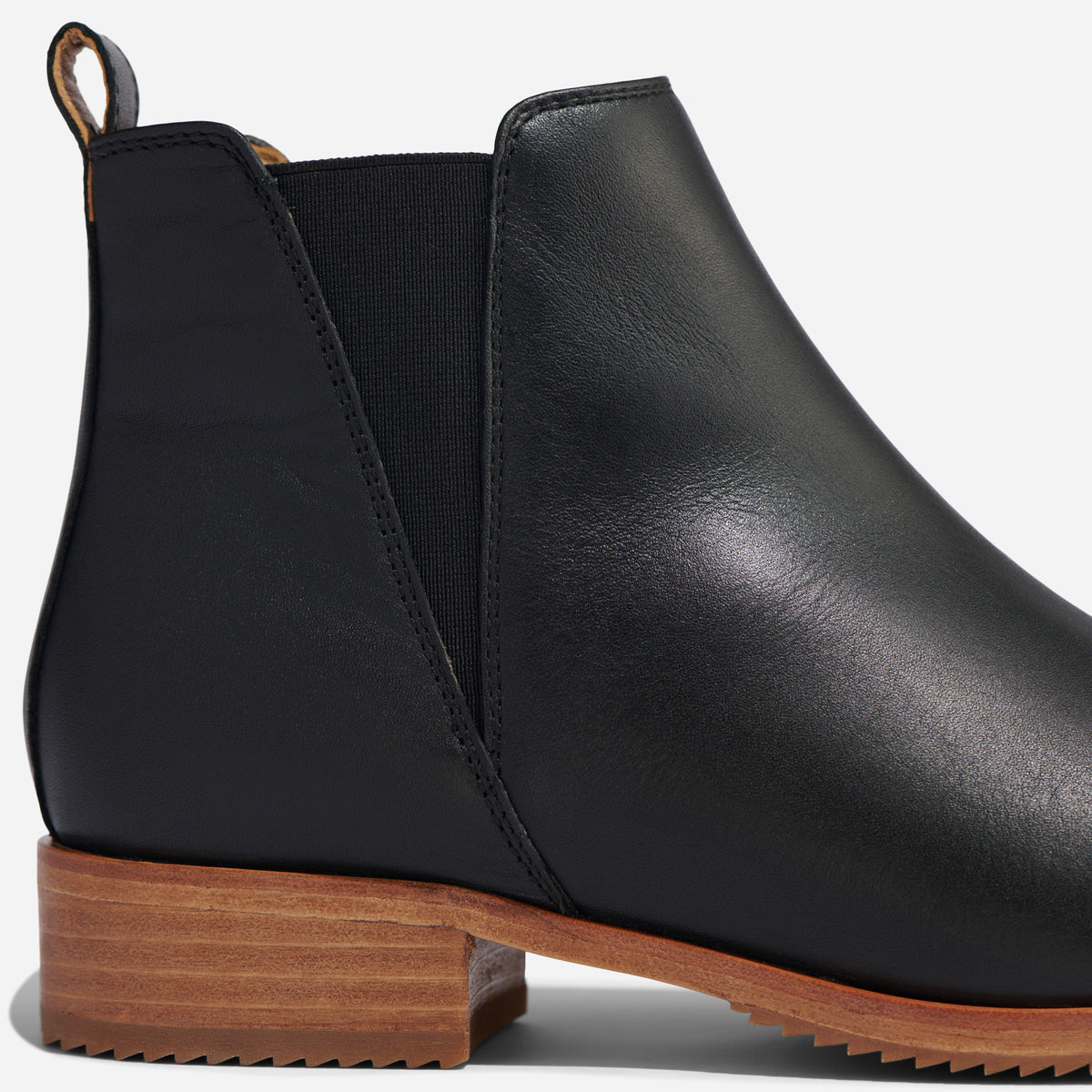 Single black leather Chelsea boot with an elastic side panel and a light brown wood-look sole.