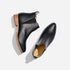 Pair of black leather Chelsea boots with tan soles and NISOLO printed on the inner heel, shown from a top-down view.