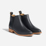 Pair of black leather Eva Everyday Chelsea boots with tan soles and elastic side panels on a white background.