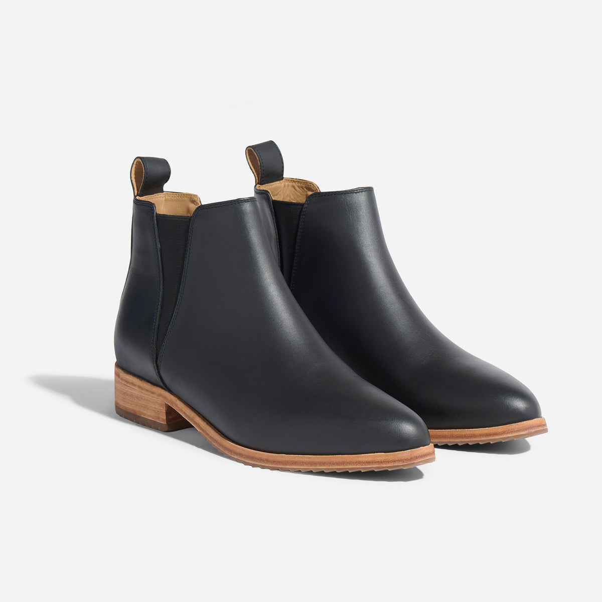 Pair of black leather Eva Everyday Chelsea boots with tan soles and elastic side panels on a white background.