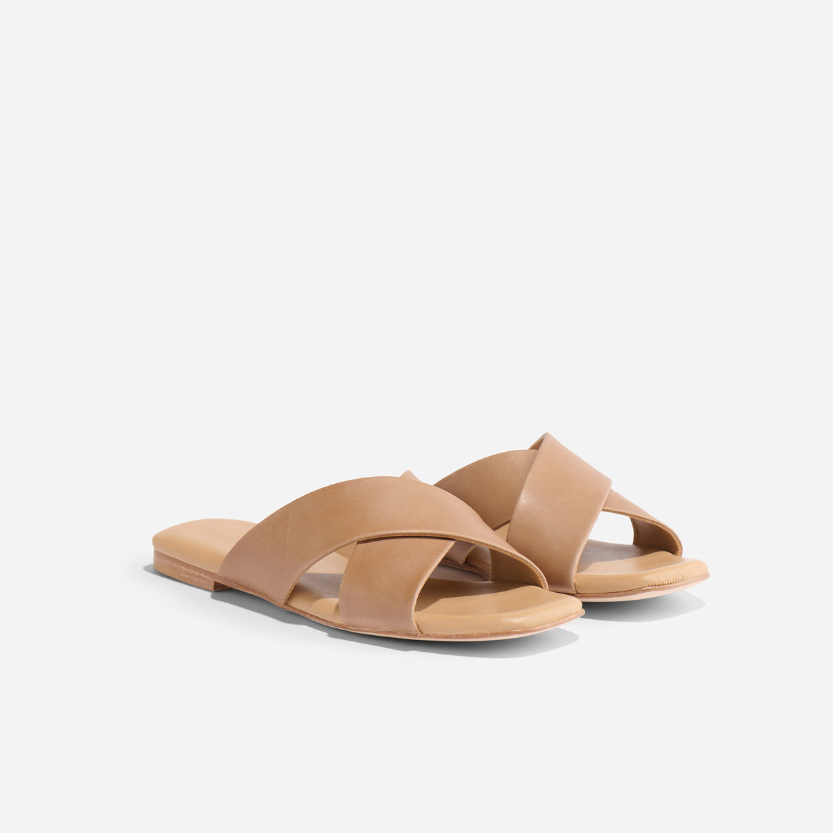 Pair of tan leather Catalina Slide Sandals with wide crisscross straps and flat soles on a white background.