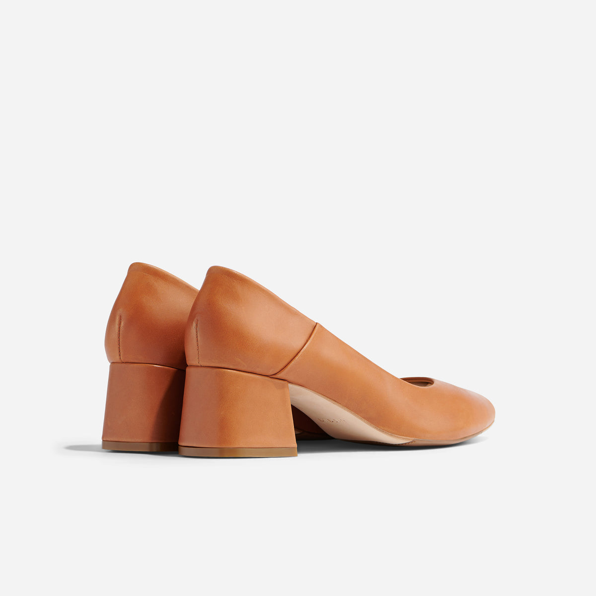 Pair of caramel leather mid-heel pumps shown from a rear side angle on a white background.