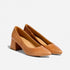 Pair of caramel leather pointed-toe pumps with a mid-height block heel on a white background.