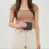 A person holds a small, square black leather Remi Zip Wallet with a gold zipper and the NISOLO brand name embossed.
