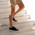 A pair of black leather Diego Everyday Sneakers with white soles worn by a person walking down stone stairs.